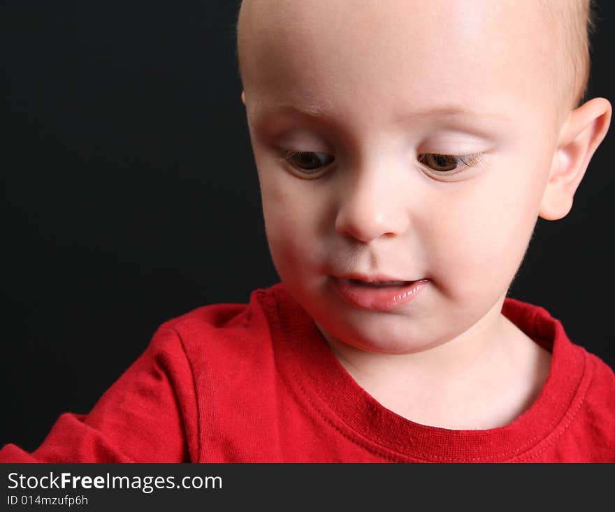 Blond toddler against a black background with a serious expression