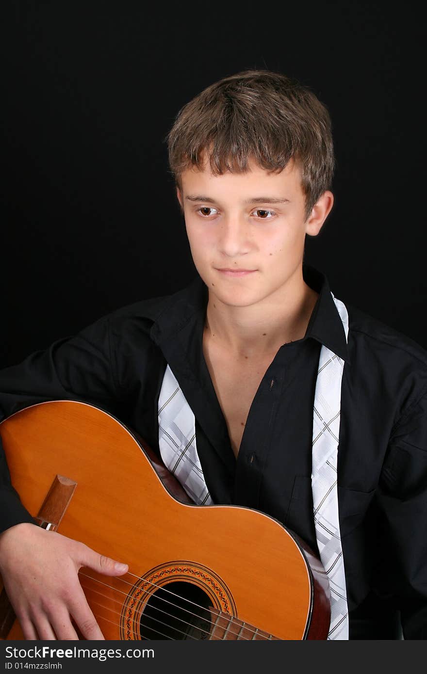 Teenage male in casual attire playing guitar. Teenage male in casual attire playing guitar