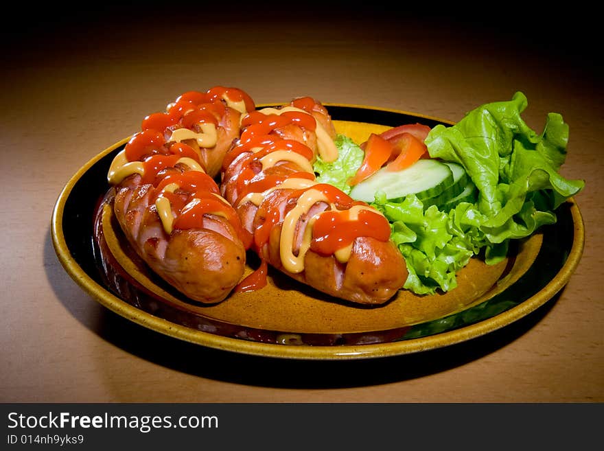 Sausages on plate with tomatoes and salad. Sausages on plate with tomatoes and salad