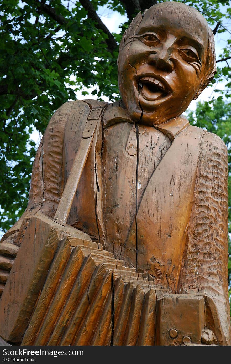 A wooden musician playing an accordion
