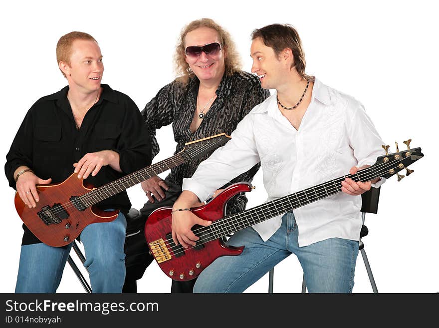 Three sitting men with two guitars. Talking music