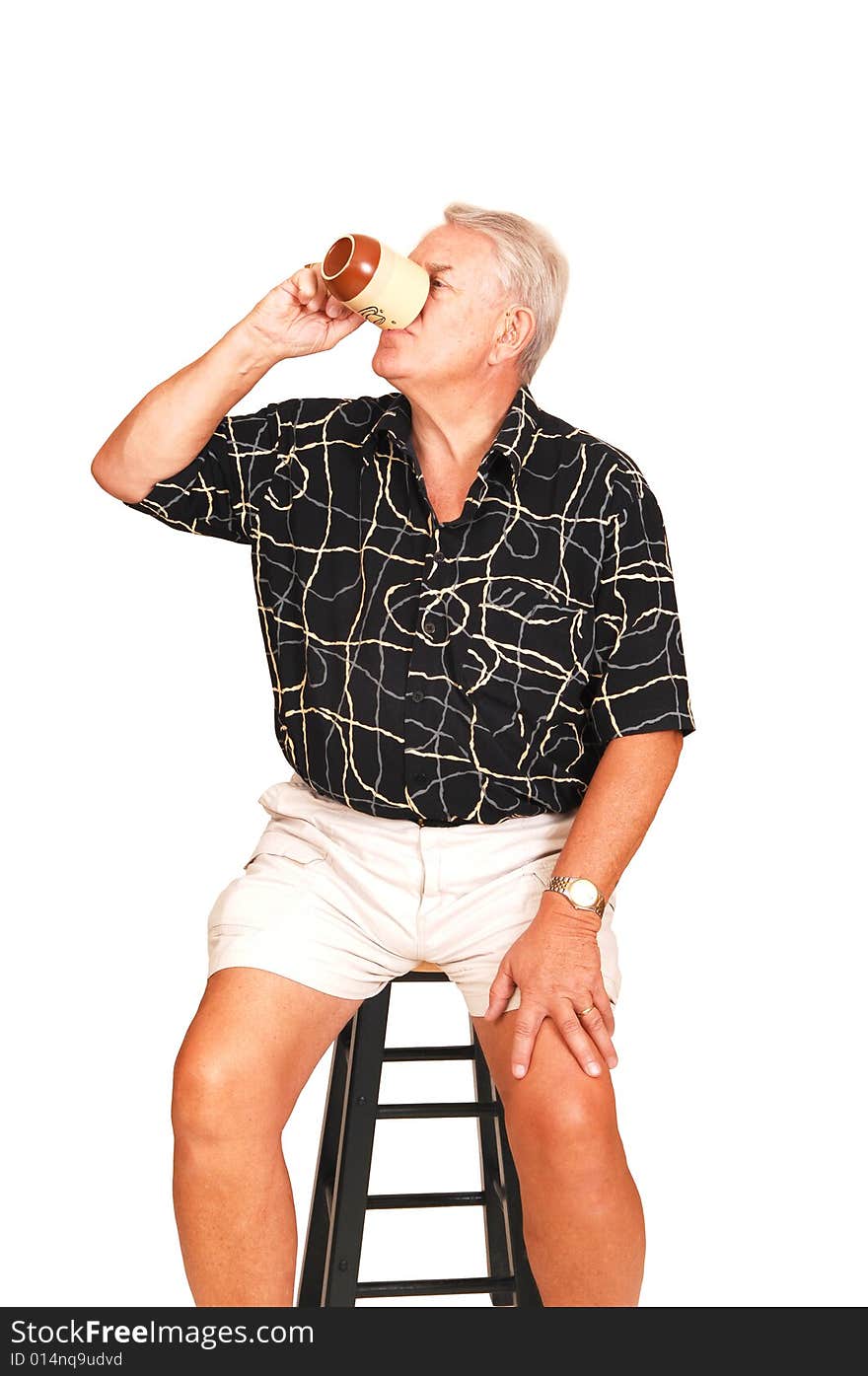 An senior in shorts sitting on a bar chair having a good coffee. An senior in shorts sitting on a bar chair having a good coffee.