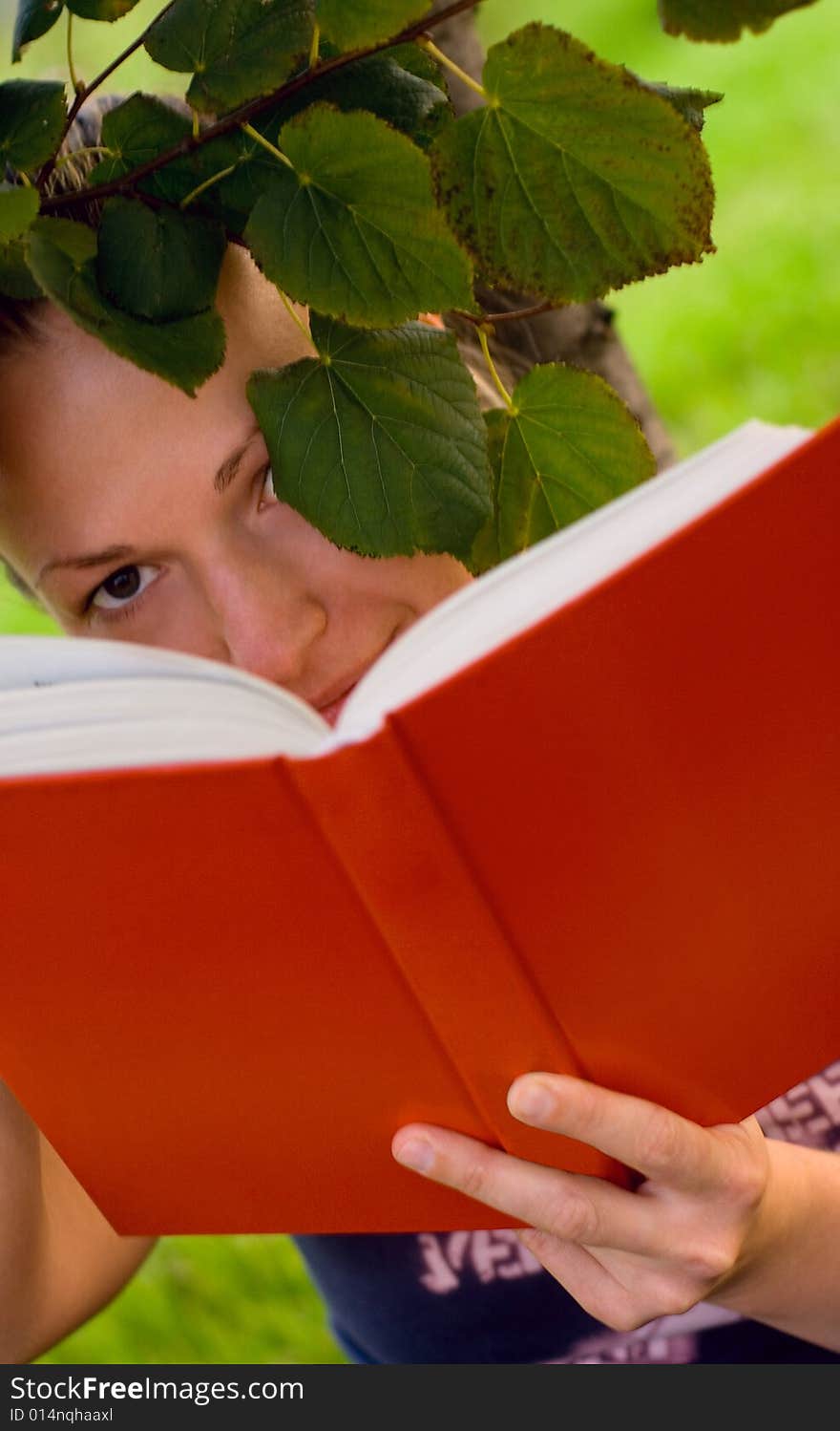 Portrait of pretty young woman with book under the tree