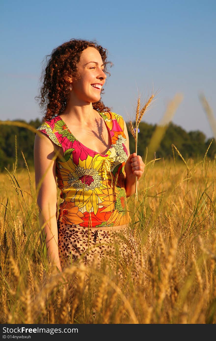 Young woman stands on a wheaten field