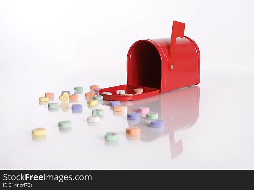 Candy valentine hearts in front of a red mailbox isolated against white background. Candy valentine hearts in front of a red mailbox isolated against white background