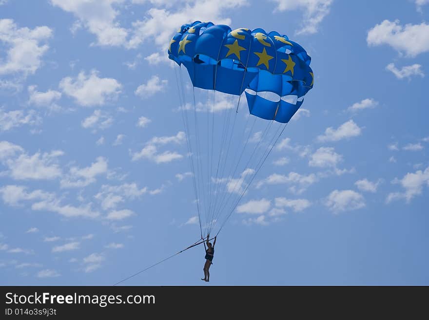 Man with a blue paraglider flying in the sky