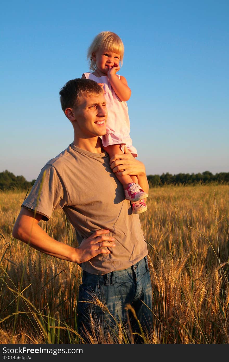 Father hold daughter on shoulder on wheaten field