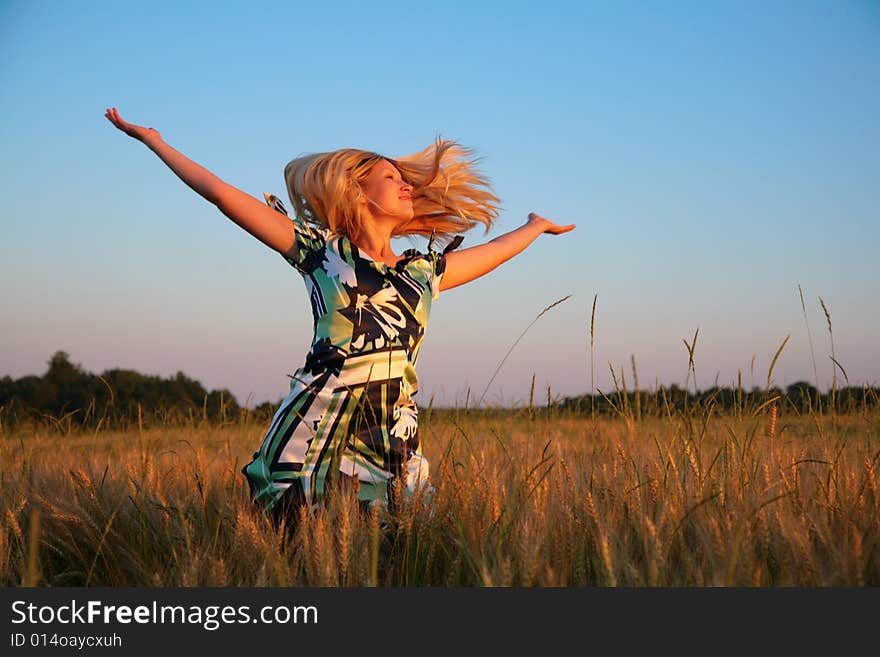 Girl with lifted hands and flying hair on wheaten