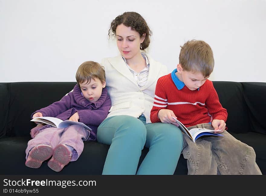 Children with mother read books on sofa