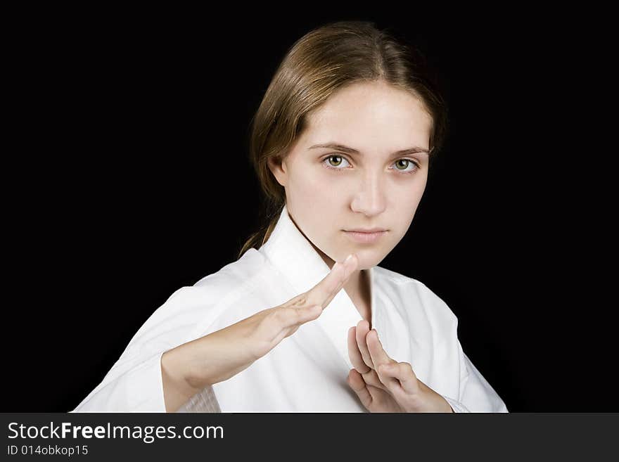 Pretty young girl in a karate pose on black background