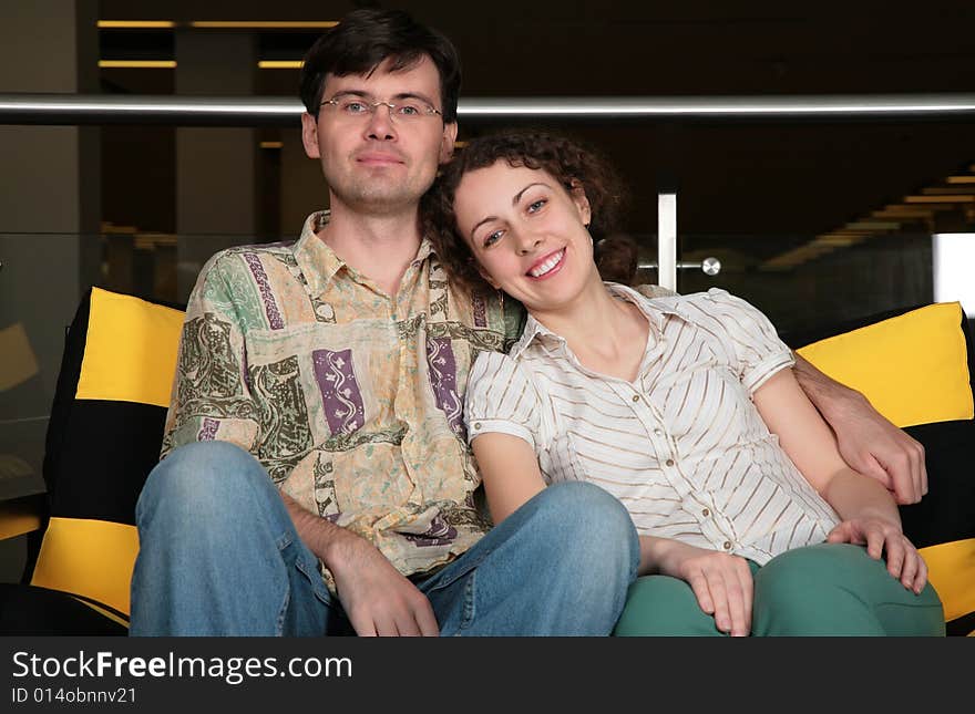 The couple sit on sofa in dark hall