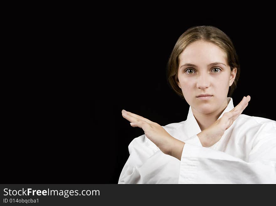 Pretty young girl in a karate pose on black background