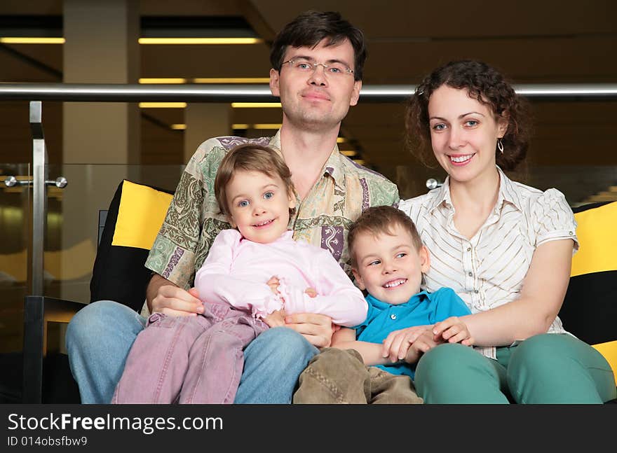 Family of three sit on sofa in dark hall. Family of three sit on sofa in dark hall