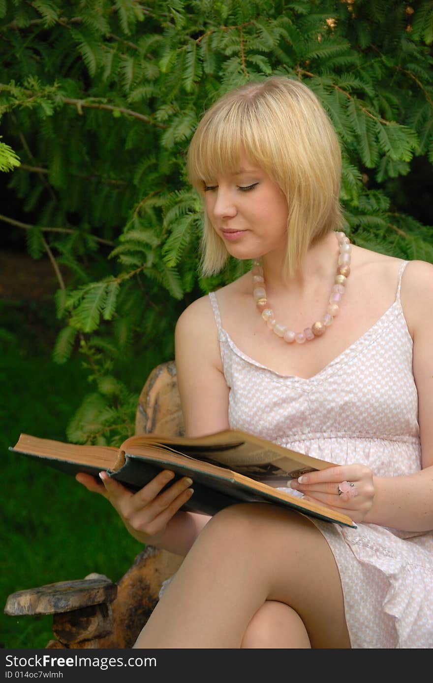 Attractive blond girl studying book in garden. Attractive blond girl studying book in garden