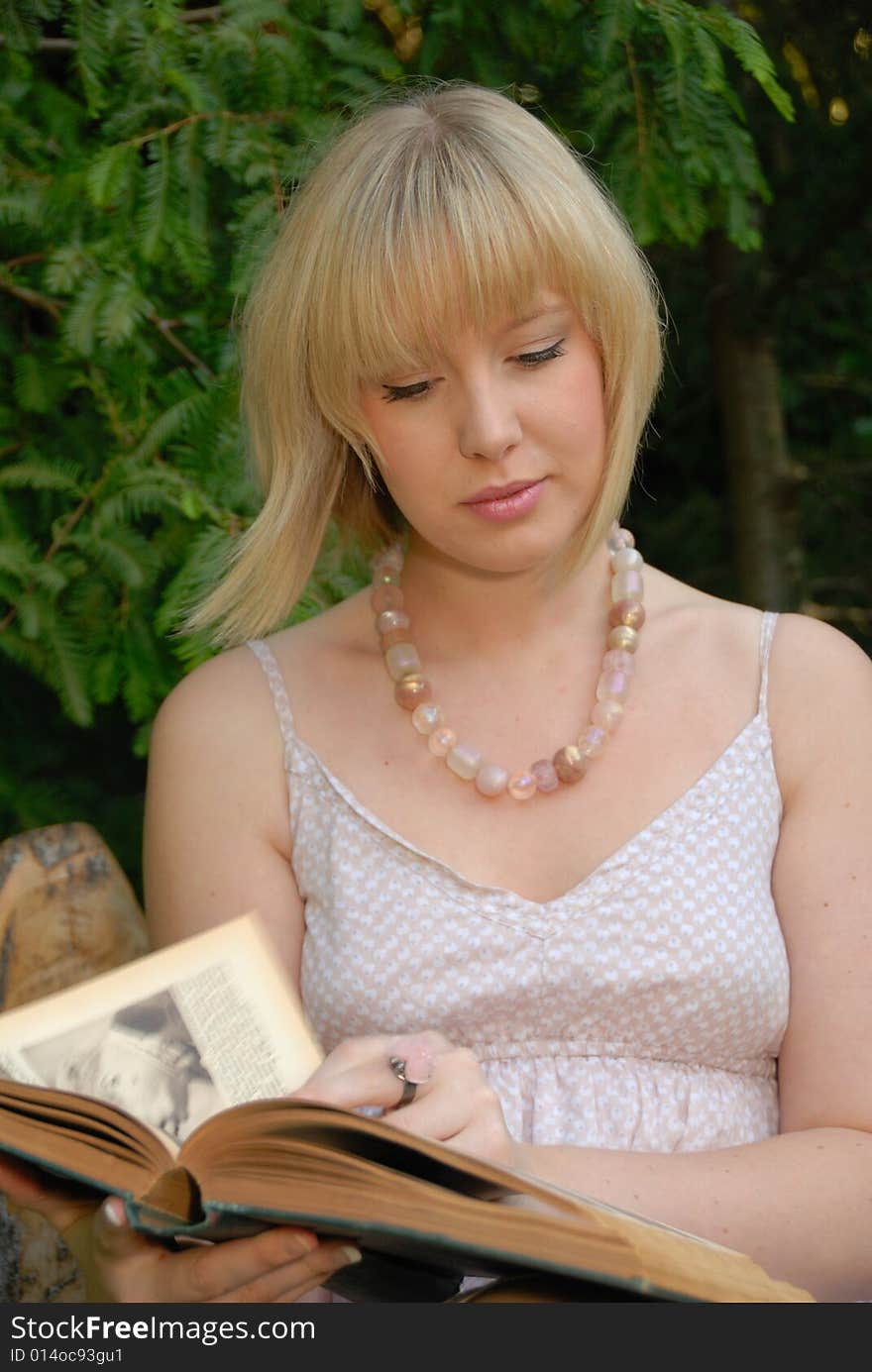 Attractive blond girl studying book in garden. Attractive blond girl studying book in garden