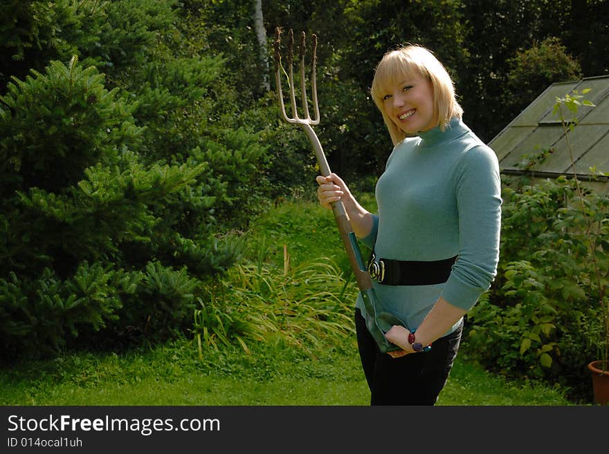 Attractive blond lady gardener smiling with fork. Attractive blond lady gardener smiling with fork