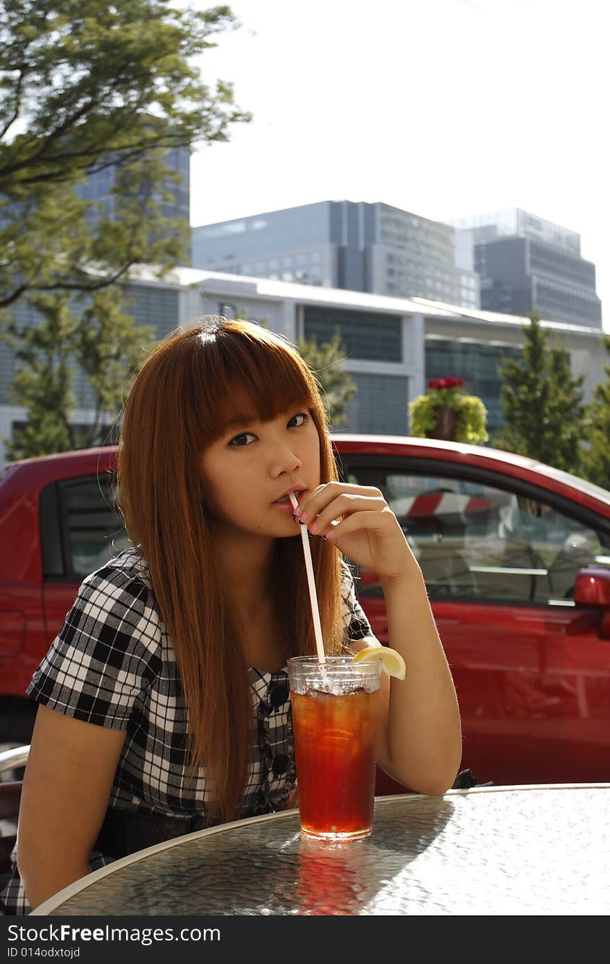 A young girl drinking lemon juice as she is sitting at a table outdoors. A young girl drinking lemon juice as she is sitting at a table outdoors.