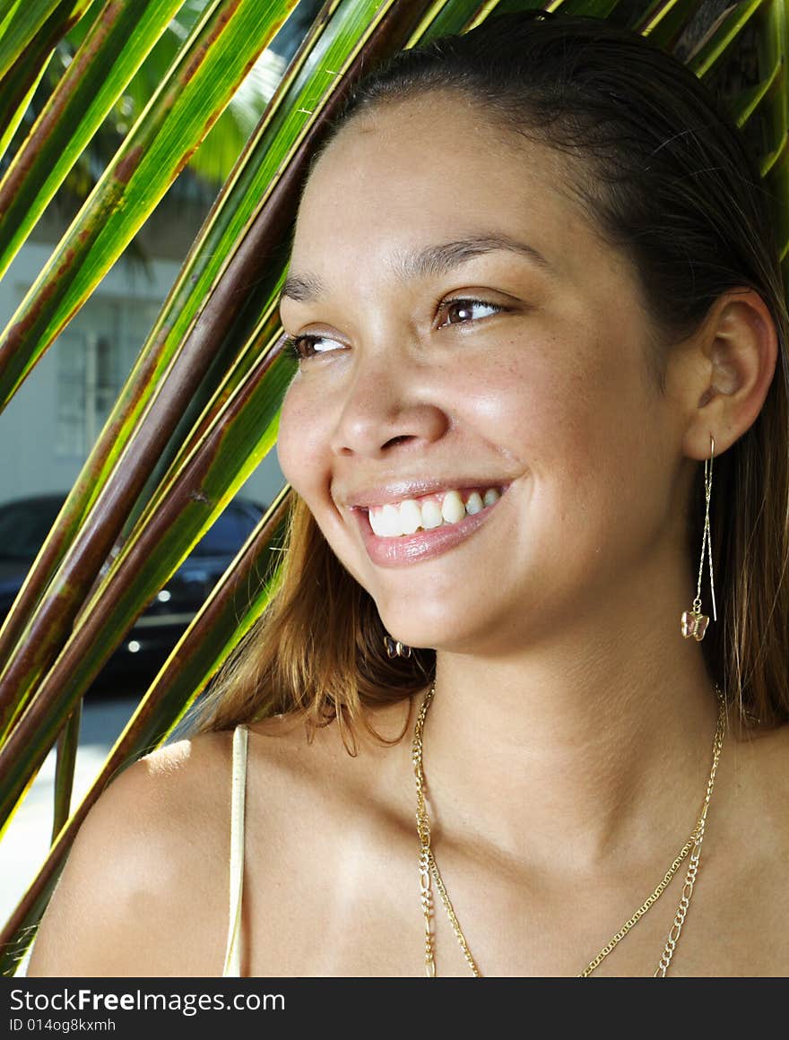 Young woman with a palm frond in the background. Young woman with a palm frond in the background.