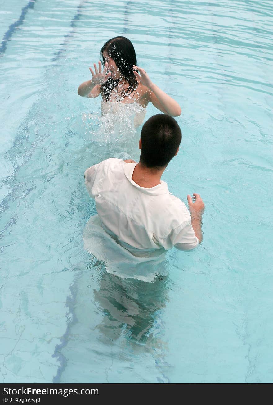 Happy couple playing in the swimming pool.