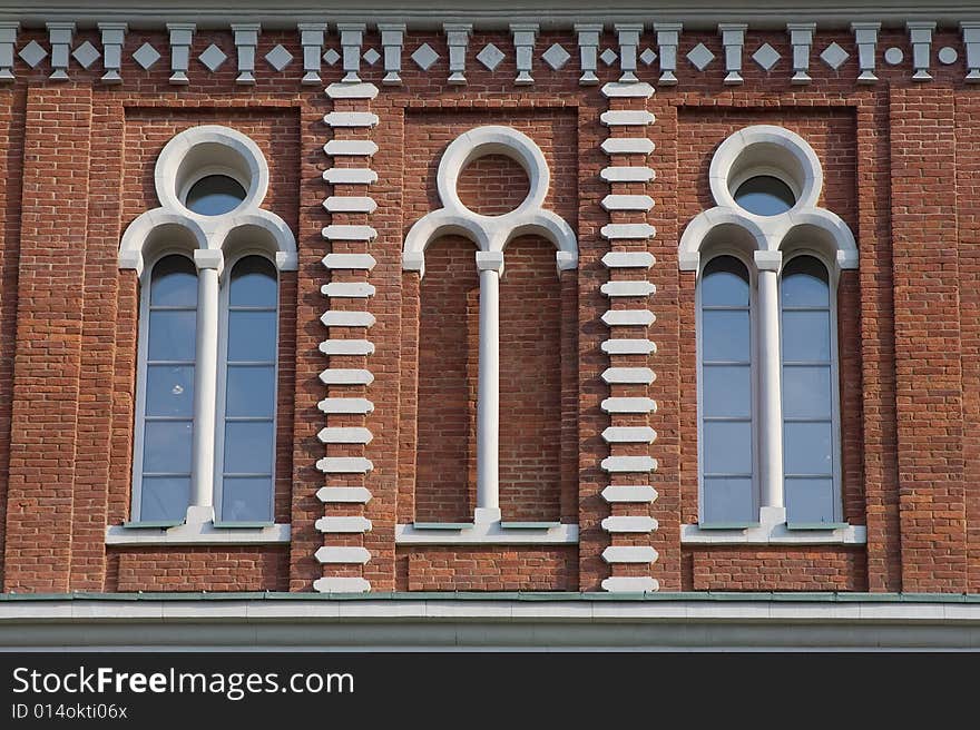 Three high glassed white-framed windows in a red brick wall