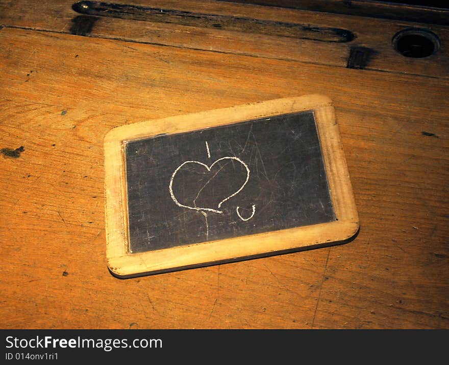 I love you scribbled on old blackboard resting on school desk. I love you scribbled on old blackboard resting on school desk