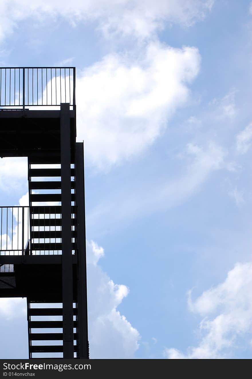 Silhouette of steel fire escape with cloudy ble sky