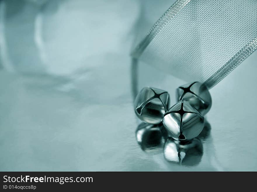 Three bells and silver ribbon reflecting onto a silver metallic background. Shallow depth of filed and selective focus used. Copyspace available. Three bells and silver ribbon reflecting onto a silver metallic background. Shallow depth of filed and selective focus used. Copyspace available.