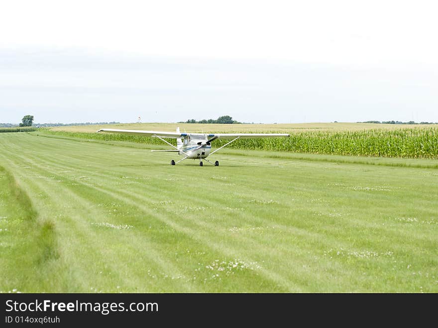 Image of a small aircraft landing on green field. Image of a small aircraft landing on green field