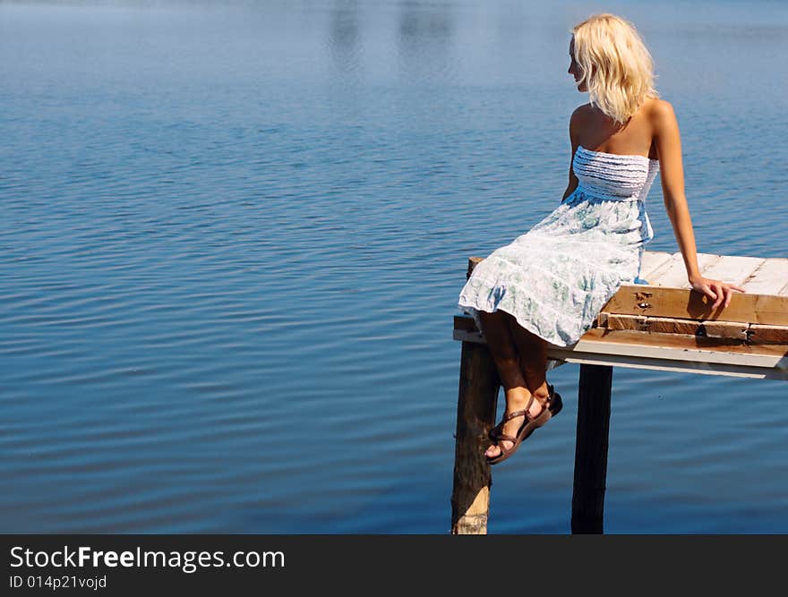 Girl sitting on a pier at the river bank