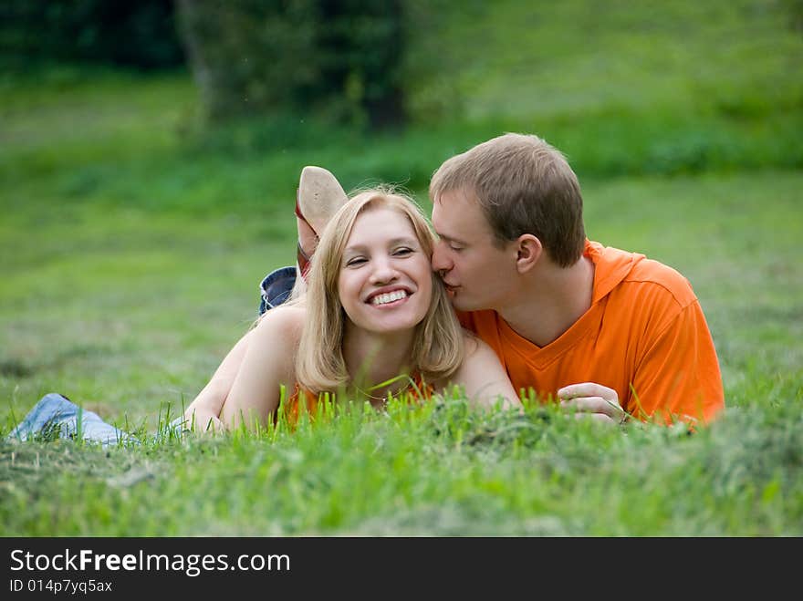 Loving couple lies and embraces on a green grass