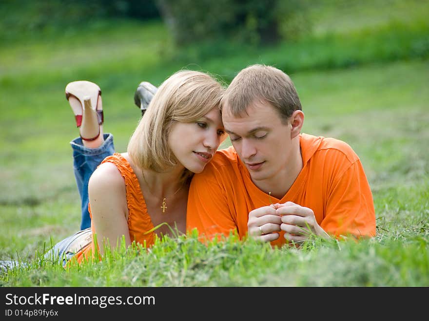 Loving couple lies and embraces on a green grass