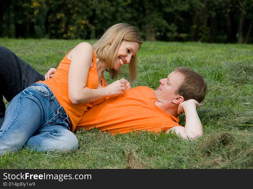 Loving couple lies on a green grass