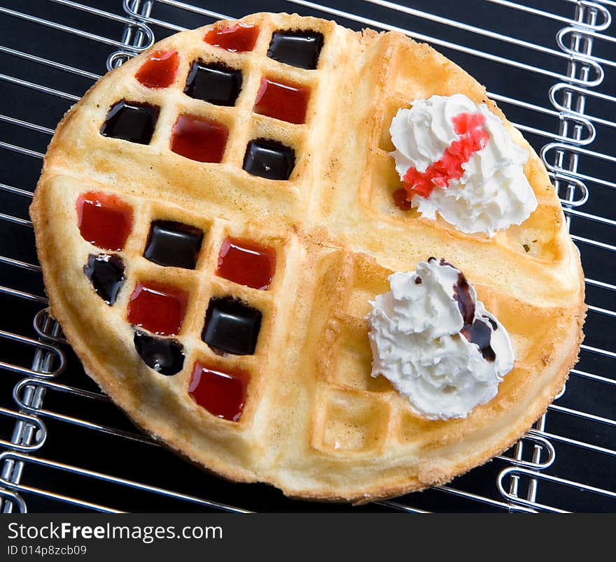 Waffle with cream and coating with chocolate and strawberry syrup