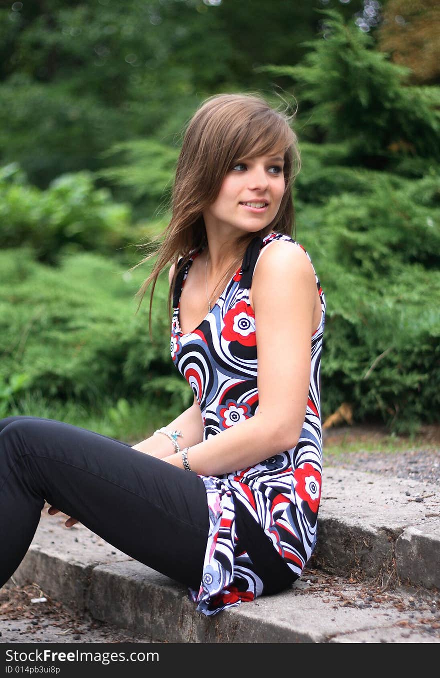 Portrait of a gorgeous girl looking at the right. She is dressed in a colorful, above the knees dress and jeans.