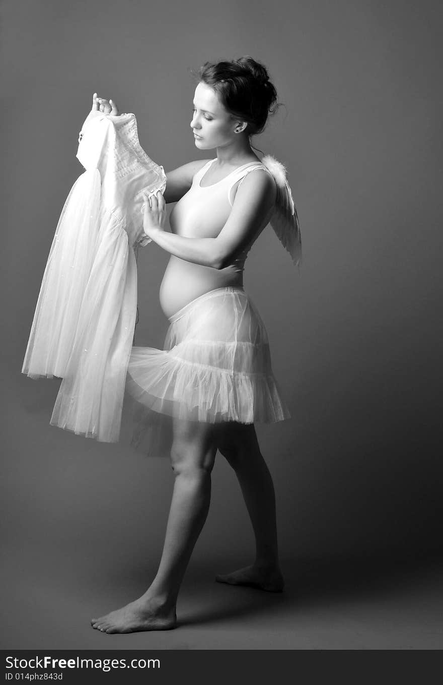 Pregnant woman on a grey background with angel wings