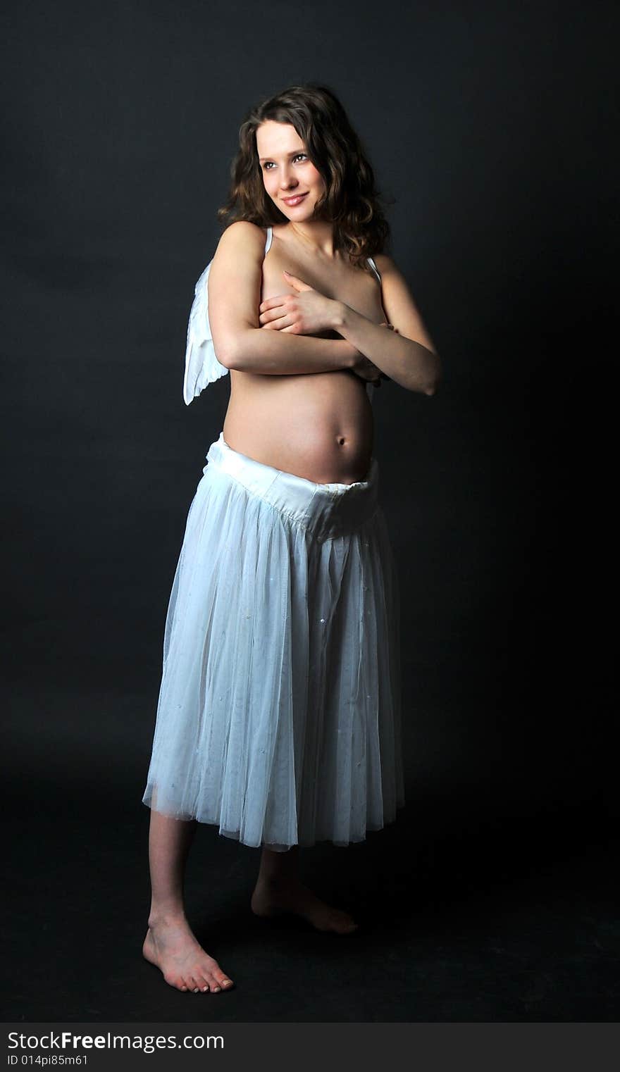 Pregnant woman on a black background with angel wings