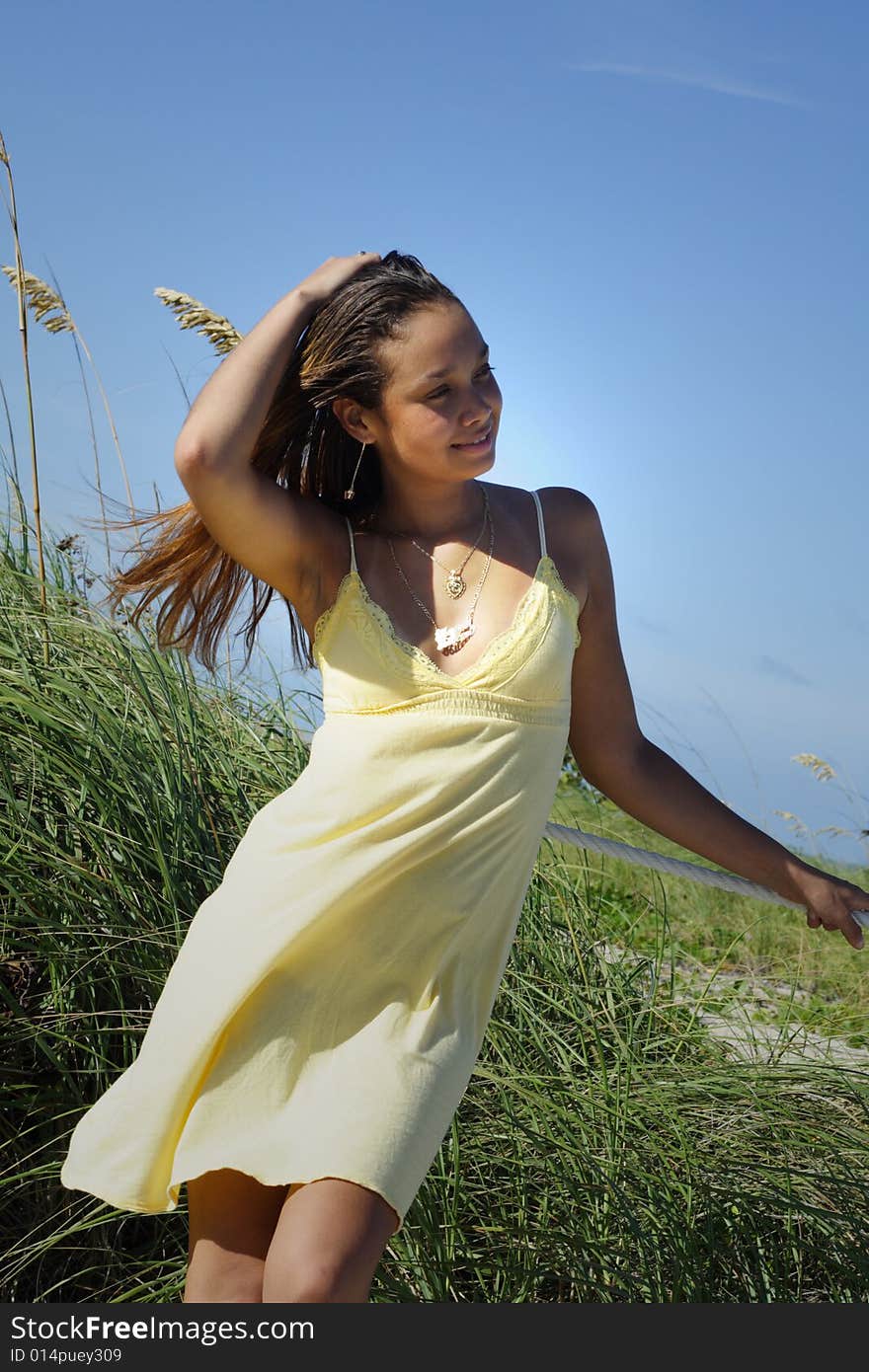 Young woman standing by sand dunes on the beach. Young woman standing by sand dunes on the beach.