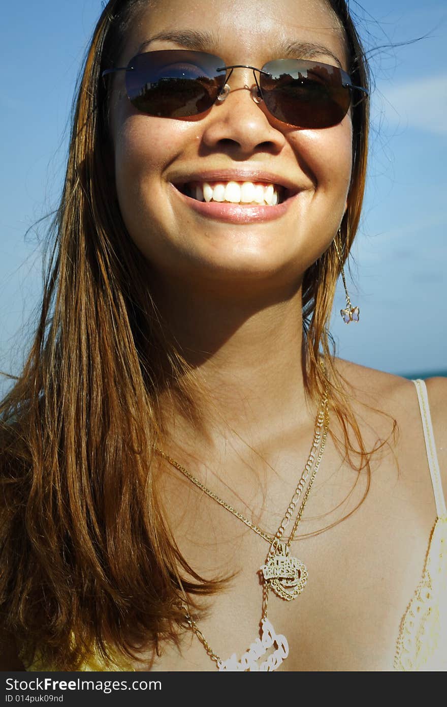 Woman smiling on a blue sky background. Woman smiling on a blue sky background