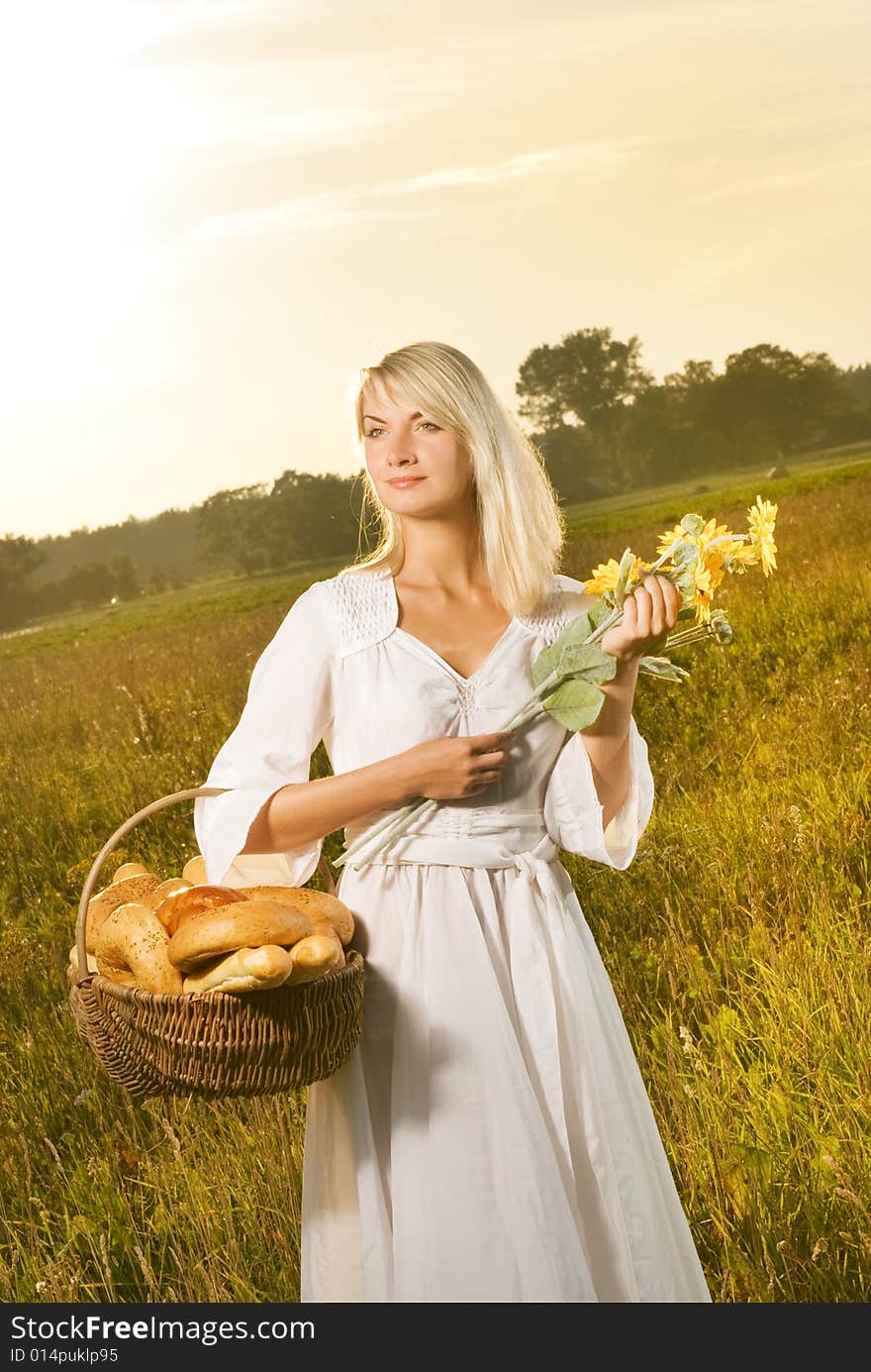 Beautiful young woman with a basket full of fresh baked bread. Beautiful young woman with a basket full of fresh baked bread