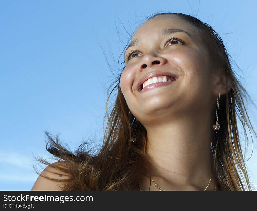 Young female smiling on a blue sky background. Young female smiling on a blue sky background