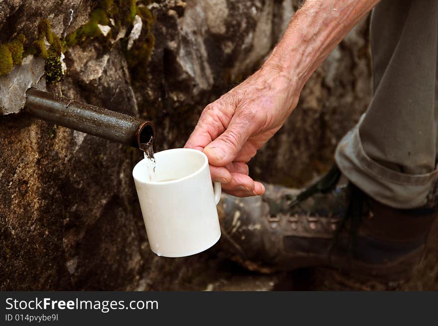 Old man hand filling a cup by water. Old man hand filling a cup by water