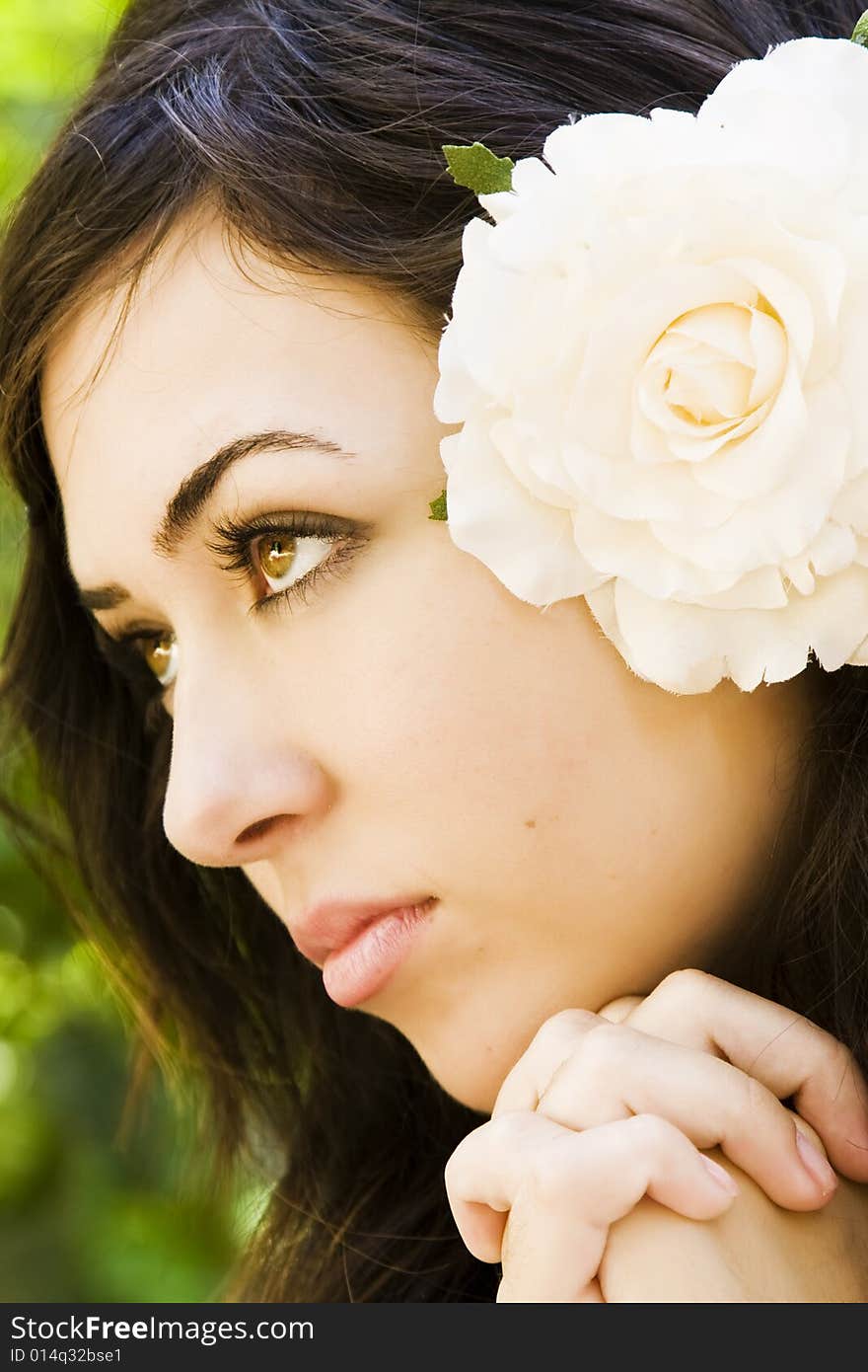 Young woman praying with a white rose in her hair.