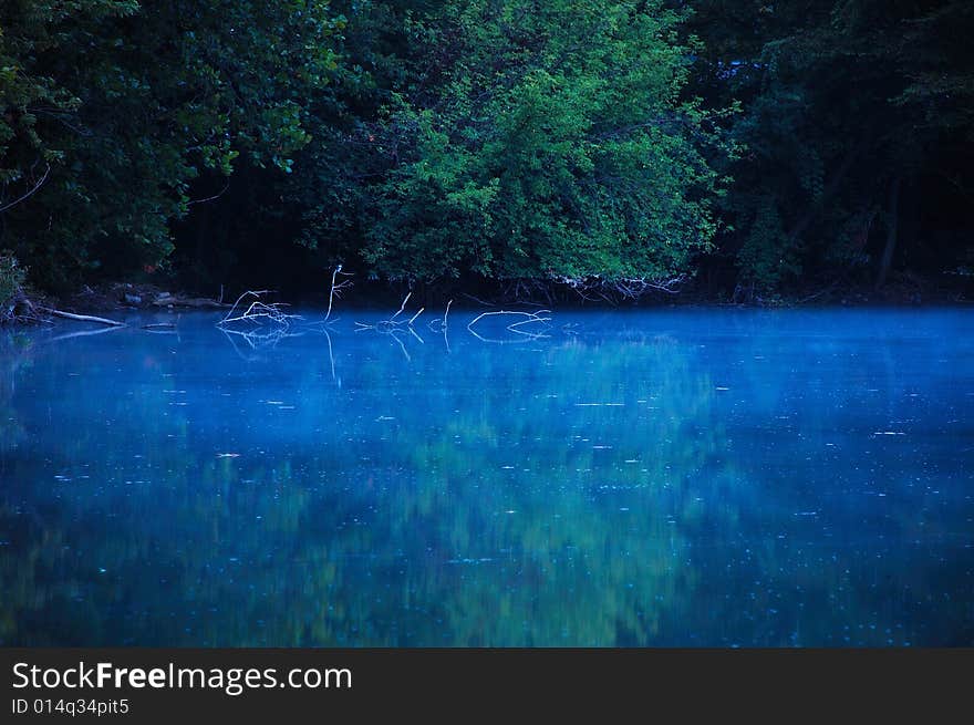 This is a early morning shot of a lake. The reflection of the tree line can be seen in the water. This is a early morning shot of a lake. The reflection of the tree line can be seen in the water.