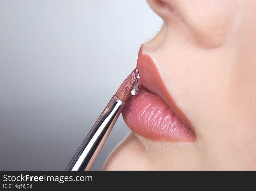 Applying liquid gloss at the lips, moisturizing them. Applying liquid gloss at the lips, moisturizing them