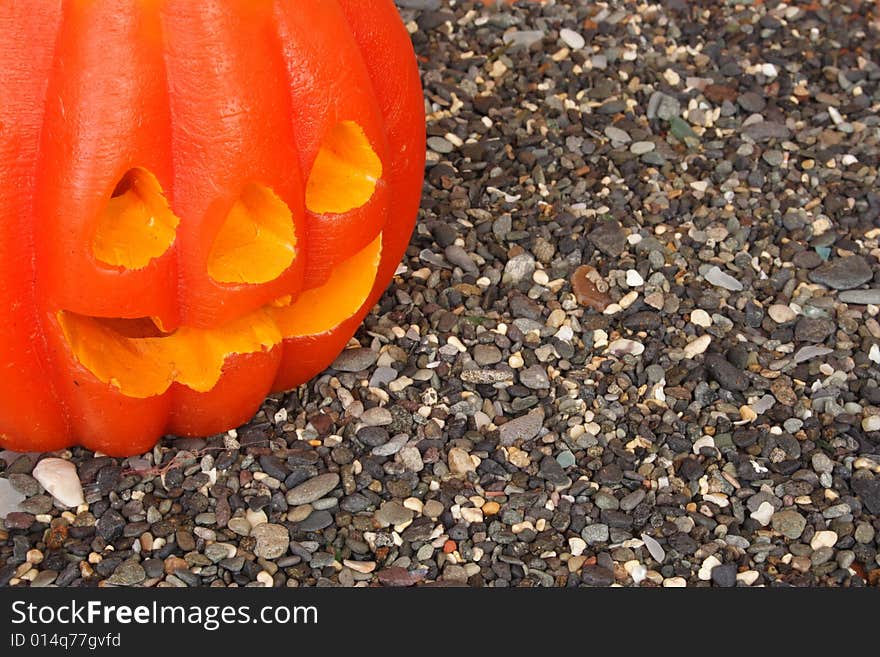 Scary Halloween pumpkin on a pebble background. Scary Halloween pumpkin on a pebble background