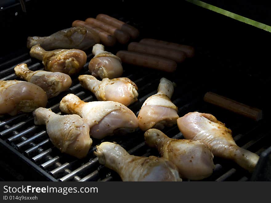 Drumsticks and hot dogs being grilled outside. Drumsticks and hot dogs being grilled outside