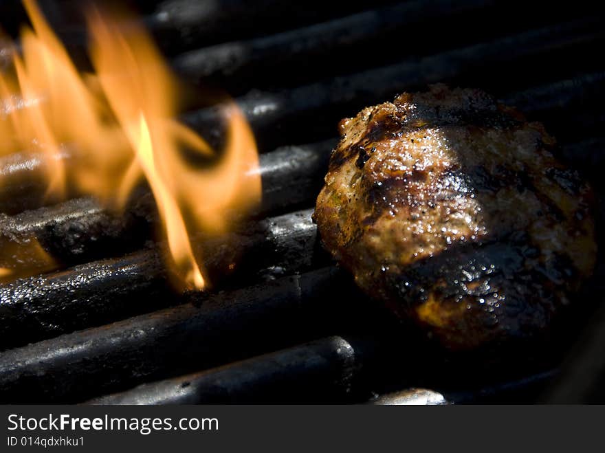 Closeup of a barbecue grills flame with a hamburger patty on it. Closeup of a barbecue grills flame with a hamburger patty on it