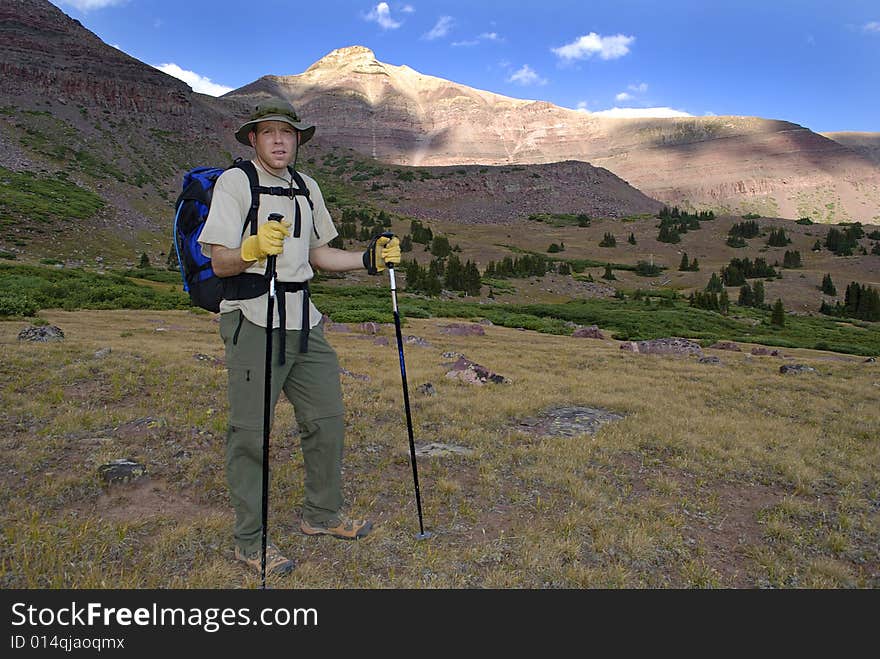 One person walking along trail with brush and mountains in background. One person walking along trail with brush and mountains in background