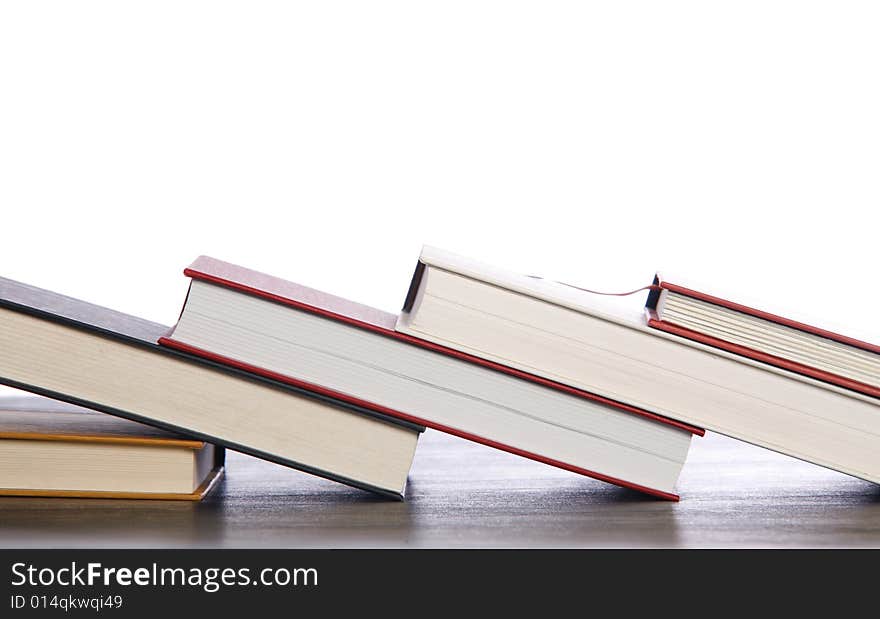 Various sized hardcover books are tipped on top of each other. Various sized hardcover books are tipped on top of each other.