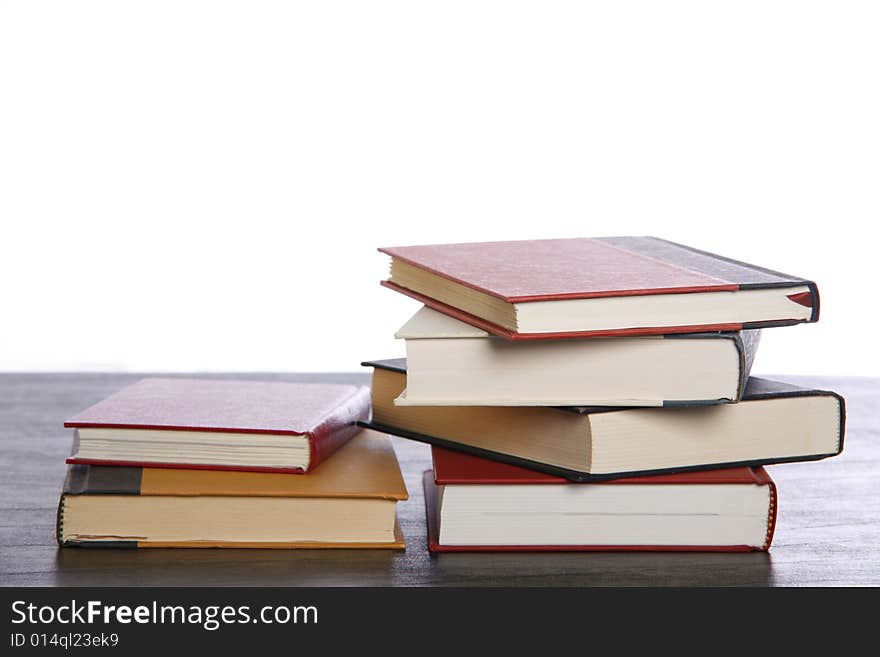 Books are stacked on a desk set against white background. Books are stacked on a desk set against white background.